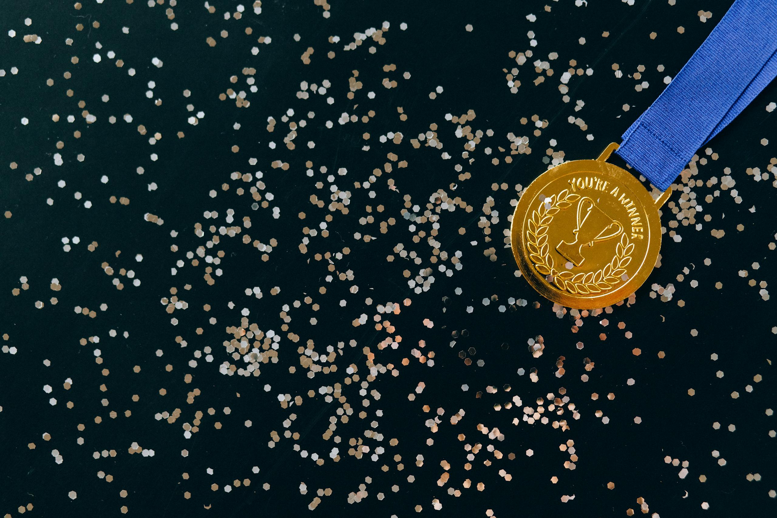 Close-Up Shot of a Gold Medal on a Black Surface