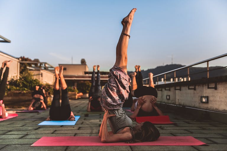 Group of Women Lying on Yoga Mat Under Blue Sky